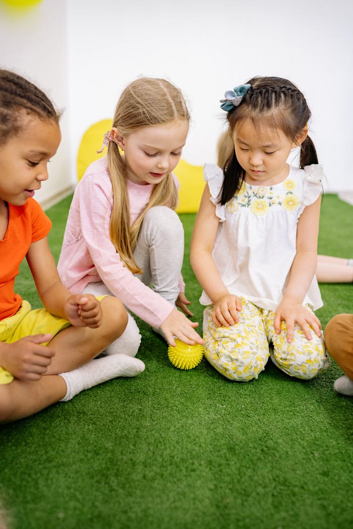 Young children of diverse backgrounds playing indoors with a ball.